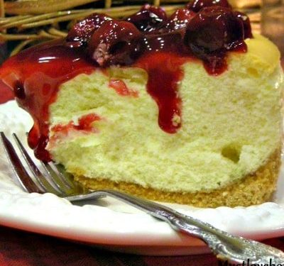 Tall New York Cheesecake on a white plate with a fork