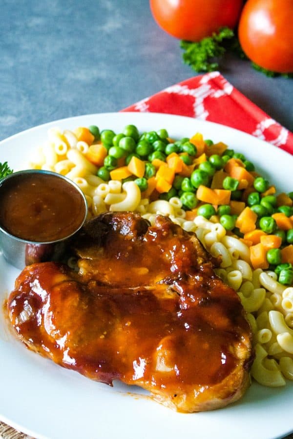 Oven BBQ Pork Chops are pork chops marinated in a bold mixture of Italian dressing, steak seasoning and worcestershire sauce, then baked with a coating of tangy barbecue sauce. #mustlovehomecooking