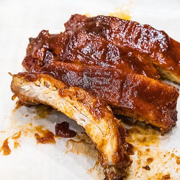 Best Ever Oven BBQ Ribs are moist, fall off the bone pork, smothered in a crispy, caramelized BBQ sauce. #mustlovehomecooking