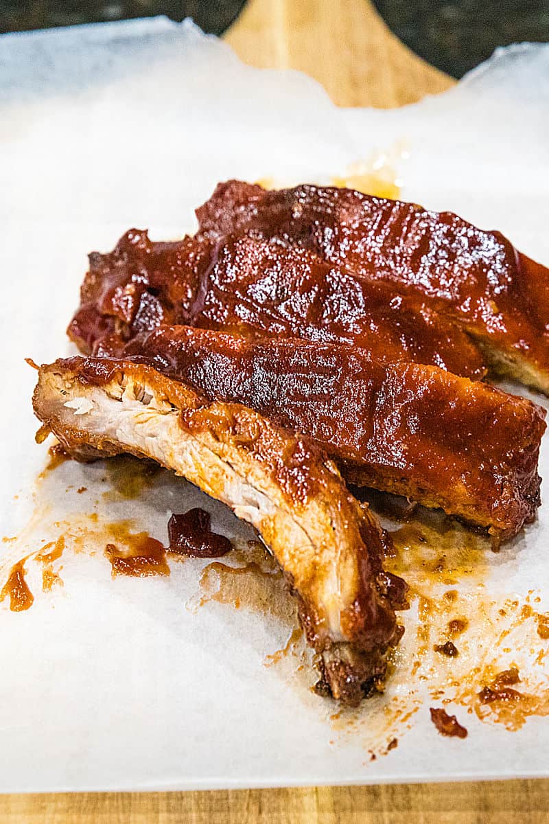 Best Ever Oven BBQ Ribs are moist, fall off the bone pork, smothered in a crispy, caramelized BBQ sauce. #mustlovehomecooking