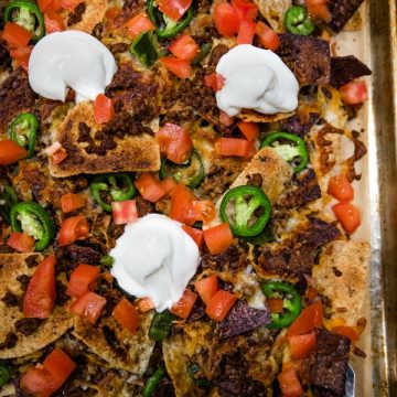 Ultimate Beef Nachos are oven crispy tortilla chips drenched in melted cheese, spicy meat and peppers. Perfect for game day, parties and a sheet pan dinner.