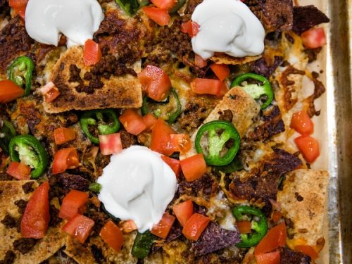 Ultimate Beef Nachos are oven crispy tortilla chips drenched in melted cheese, spicy meat and peppers. Perfect for game day, parties and a sheet pan dinner.