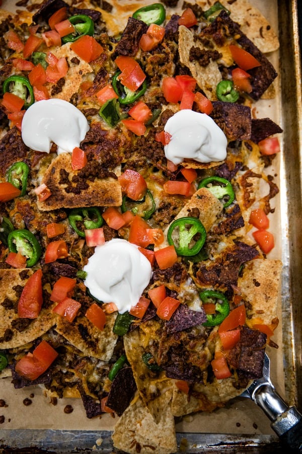 Ultimate Beef Nachos are oven crispy tortilla chips drenched in melted cheese, spicy meat and peppers. Perfect for game day, parties and a sheet pan dinner.