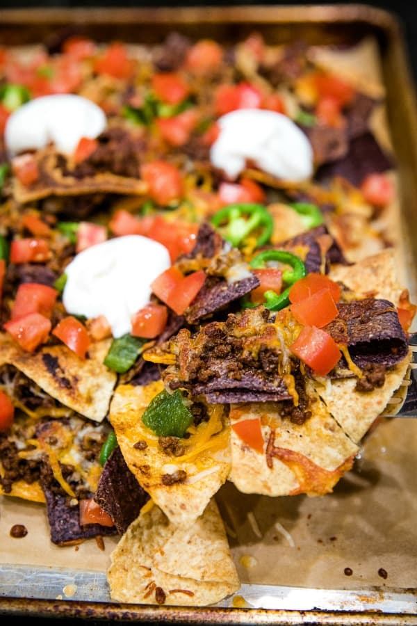 Ultimate Beef Nachos are oven crispy tortilla chips drenched in melted cheese, spicy meat and peppers. Perfect for game day, parties and a sheet pan dinner.