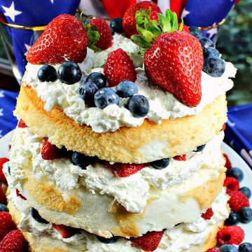 Patriotic Angel Food Cake is layers of fluffy angel food cake, stuffed with a cream cheese filling and then fruit mounded in the layers and on top. A perfect summer dessert! #mustlovehomecooking