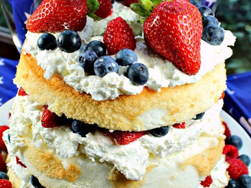 Patriotic Angel Food Cake is layers of fluffy angel food cake, stuffed with a cream cheese filling and then fruit mounded in the layers and on top. A perfect summer dessert! #mustlovehomecooking