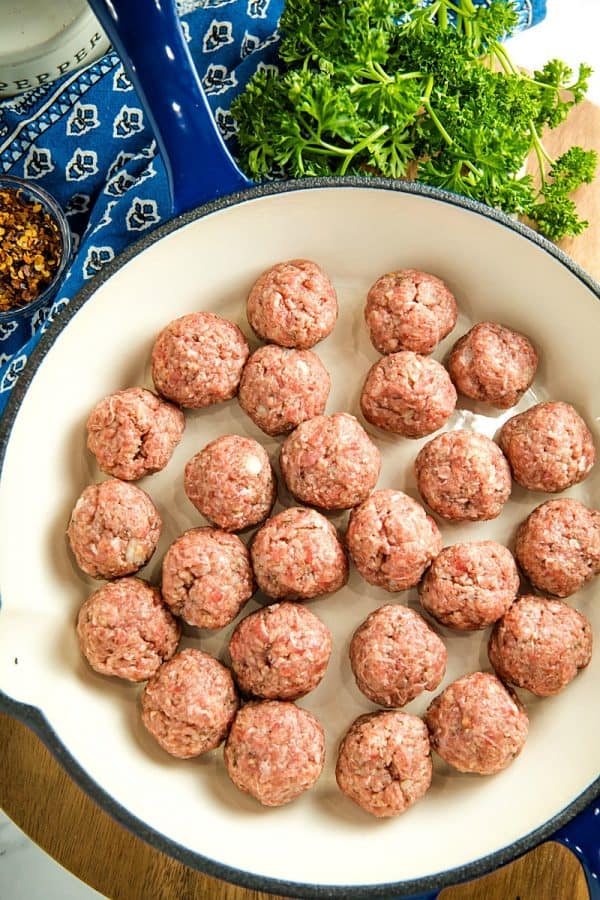 Seasoned rolled meatballs in blue skillet ready for cooking