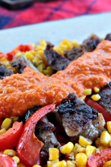 Skirt Steak with Red Pepper Puree is marinated then grilled skirt steak drenched in a smooth and flavorful red pepper puree. Served with pan fried peppers, corn and red onion.