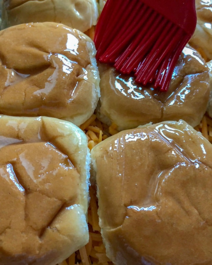 maple butter being brushed on rolls with red silicone brush