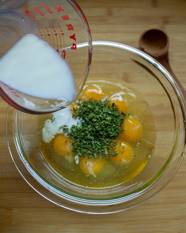 cracked eggs, chices and milk in a glass mixing bowl