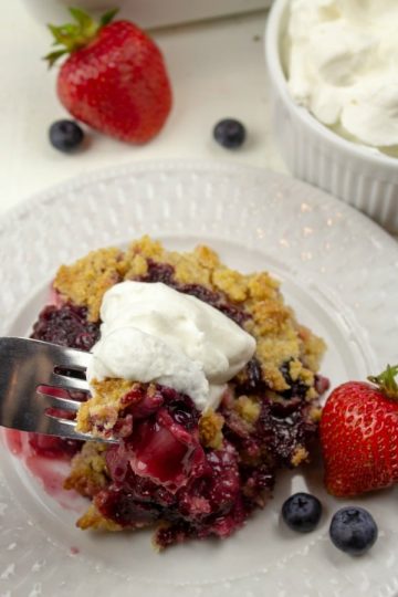classic berry cobbler with whipped cream on fork