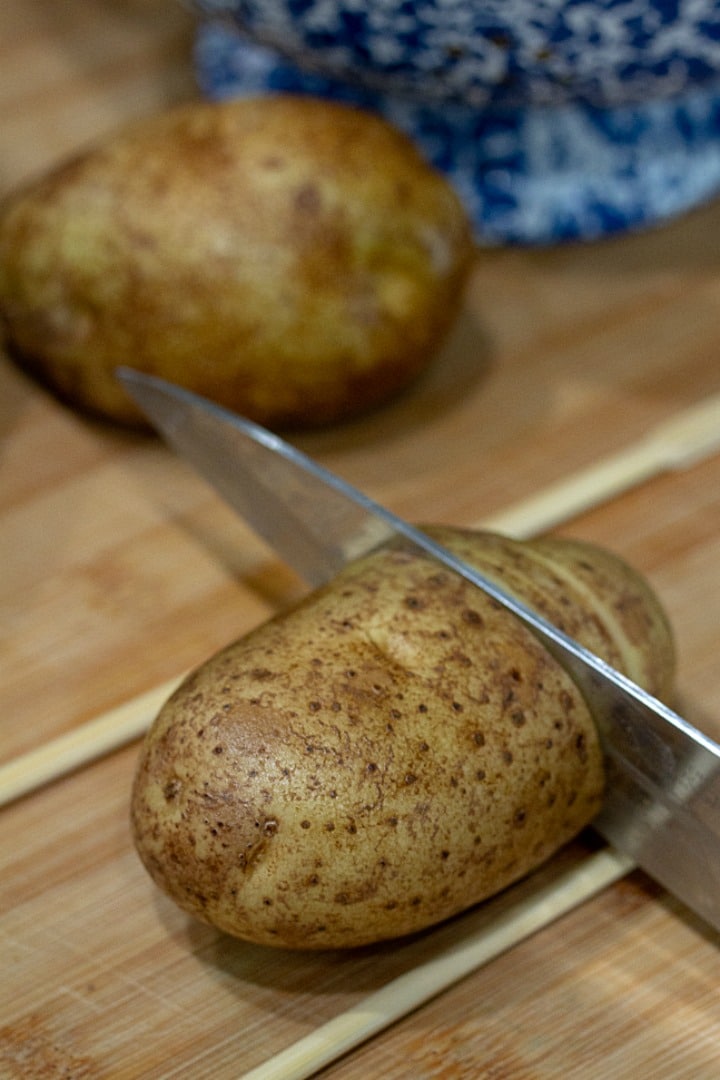 slicing hasselback potatoes with knife and chopsticks