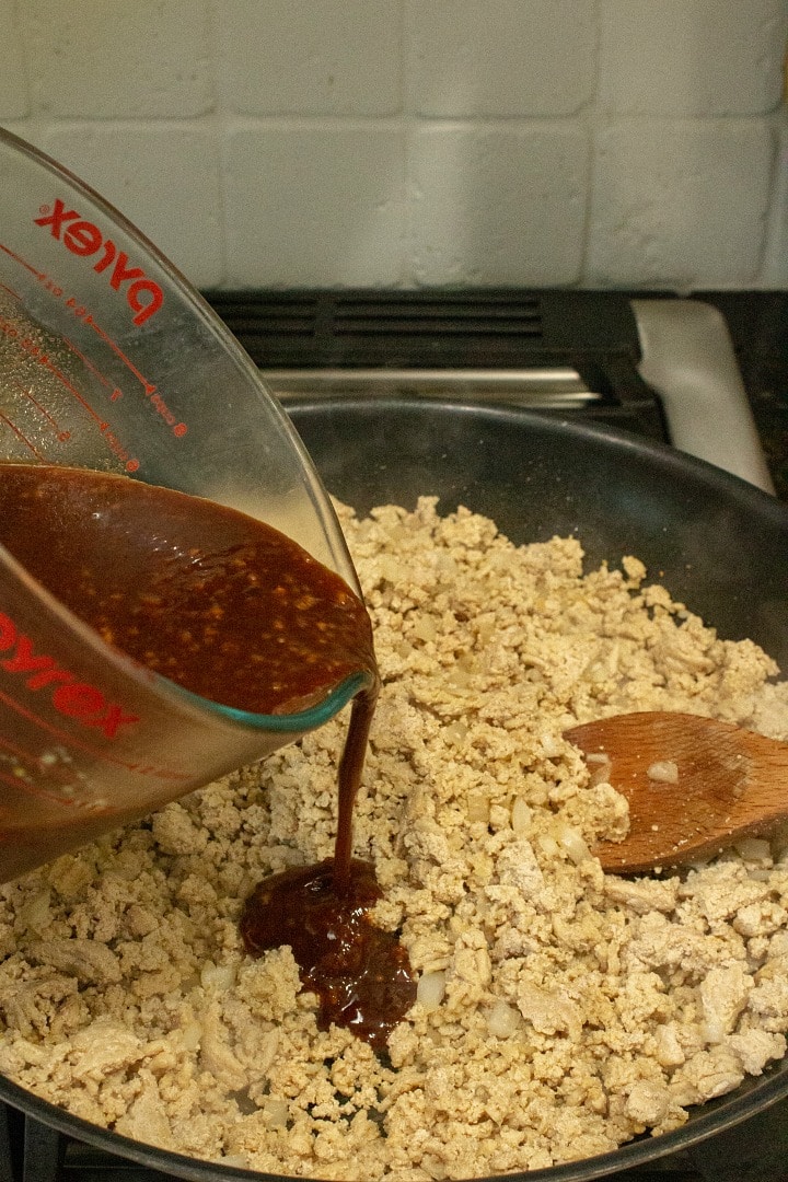 Adding Chinese chicken sauce over ground chicken in saucepan