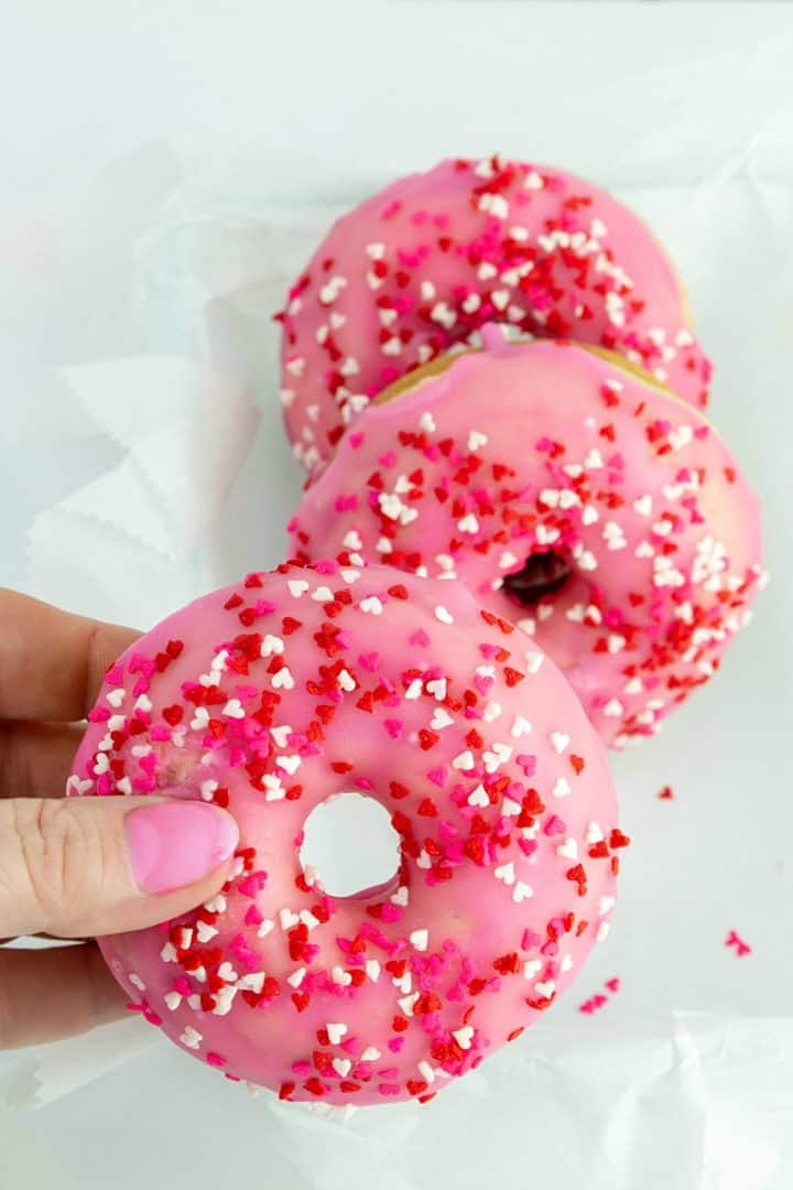 Hand holding baked valentine cherry donut
