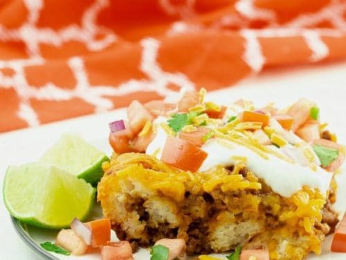 Taco Biscuit Casserole served on white plate with sour cream and pico de gallo