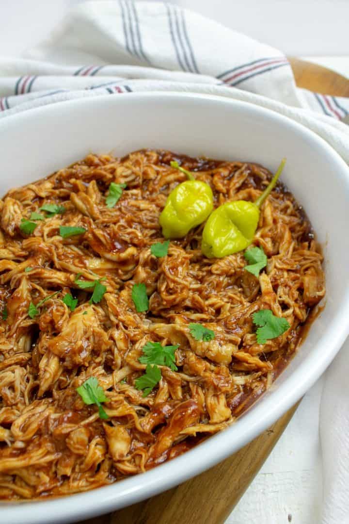 shredded BBQ chicken in serving bowl with peppers