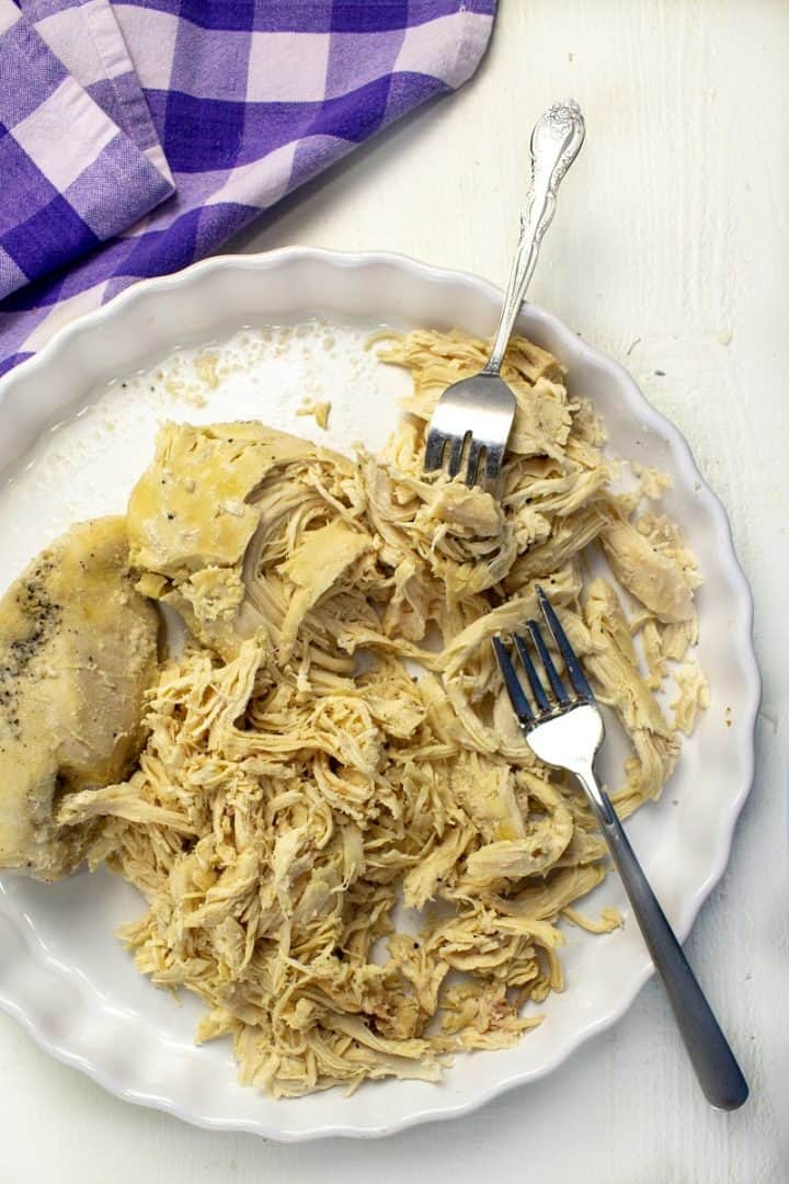 cooked chicken being shredded with two forks