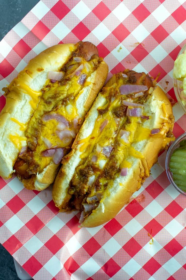 Oven Baked Cheese Dogs are great for dinner, game day parties or anytime. Quick and simple, these oven dogs are made right in the pan - with melted cheese, hot chili and a toasty bun.