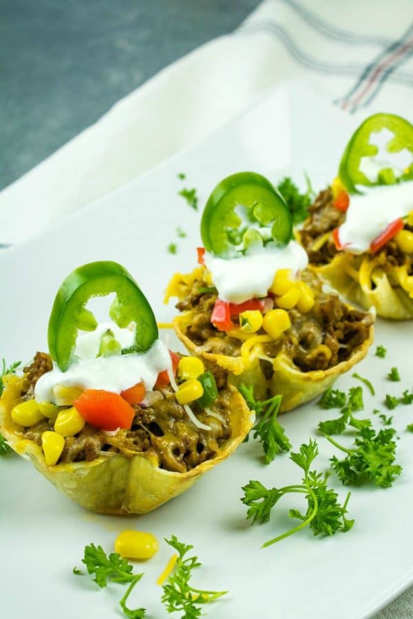 Tortilla taco cups are fun appetizers and a tasty twist on taco night. The layers of seasoned beef and melting cheese are heated in mini corn tortilla cups, then loaded with your favorite taco toppings!