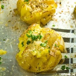 Garlic Herb Smashed Potatoes! Boiled potatoes smashed in their skins, then drizzled with butter, herbs and garlic and broiled until crispy brown. Parmesan cheese adds a tangy final touch.