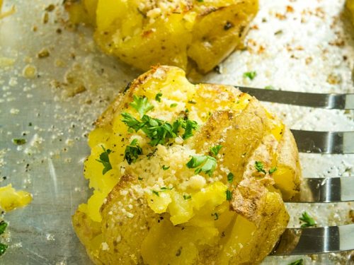 Garlic Herb Smashed Potatoes! Boiled potatoes smashed in their skins, then drizzled with butter, herbs and garlic and broiled until crispy brown. Parmesan cheese adds a tangy final touch.