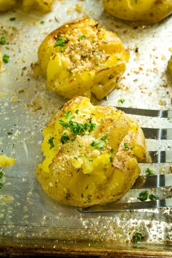 Garlic Herb Smashed Potatoes! Boiled potatoes smashed in their skins, then drizzled with butter, herbs and garlic and broiled until crispy brown. Parmesan cheese adds a tangy final touch.