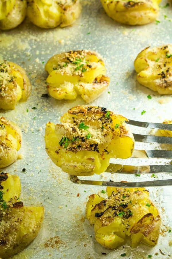 Garlic Herb Smashed Potatoes! Boiled potatoes smashed in their skins, then drizzled with butter, herbs and garlic and broiled until crispy brown. Parmesan cheese adds a tangy final touch.
