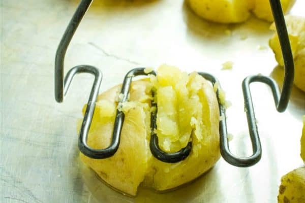 Potato masher flattening boiled potato.