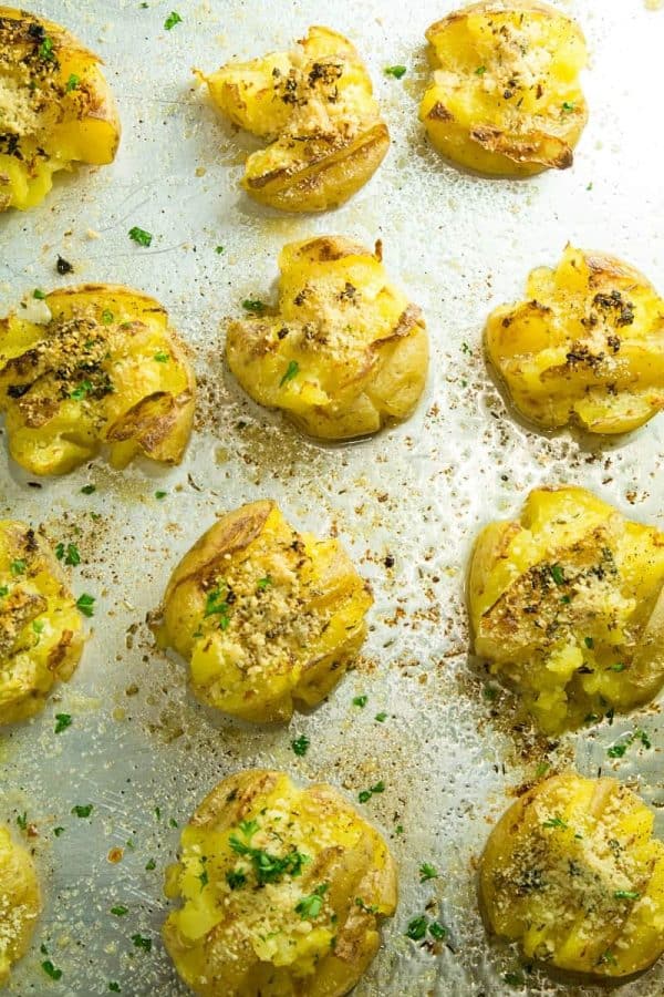 Garlic Herb Smashed Potatoes! Boiled potatoes smashed in their skins, then drizzled with butter, herbs and garlic and broiled until crispy brown. Parmesan cheese adds a tangy final touch.