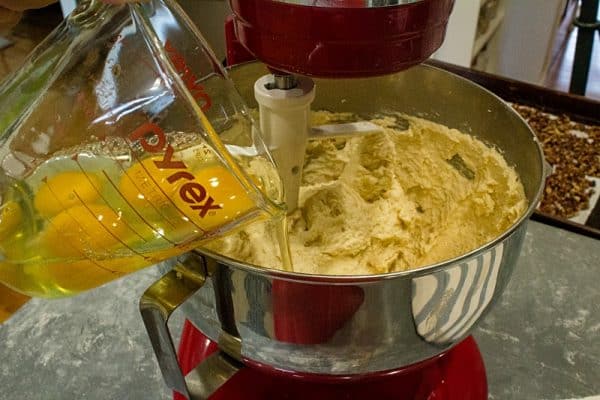 Pouring cracked eggs into cake batter.