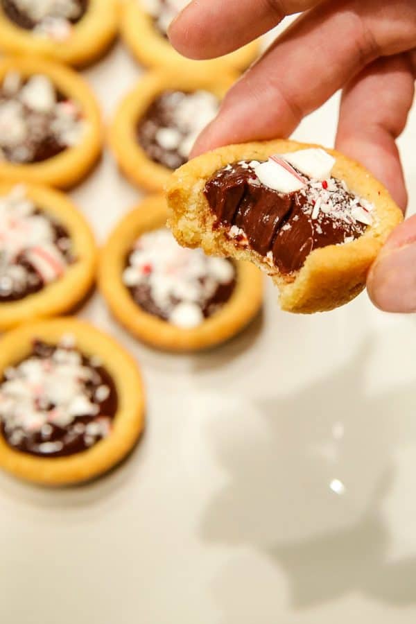 Chocolate Peppermint Sugar Cookie Cups - Tender sugar cookie cups brimming with chocolate ganache filling and crushed peppermint sprinkles! Three holiday favorites in one delicious treat!