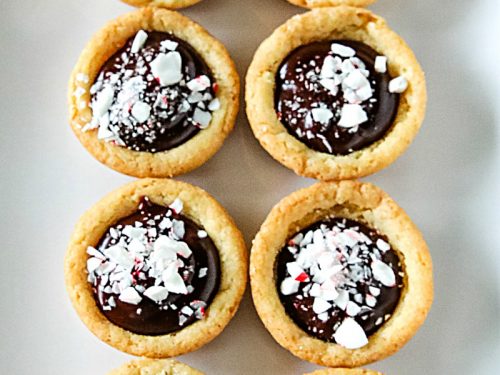 Chocolate Peppermint Sugar Cookie Cups - Tender sugar cookie cups brimming with chocolate ganache filling and crushed peppermint sprinkles! Three holiday favorites in one delicious treat!