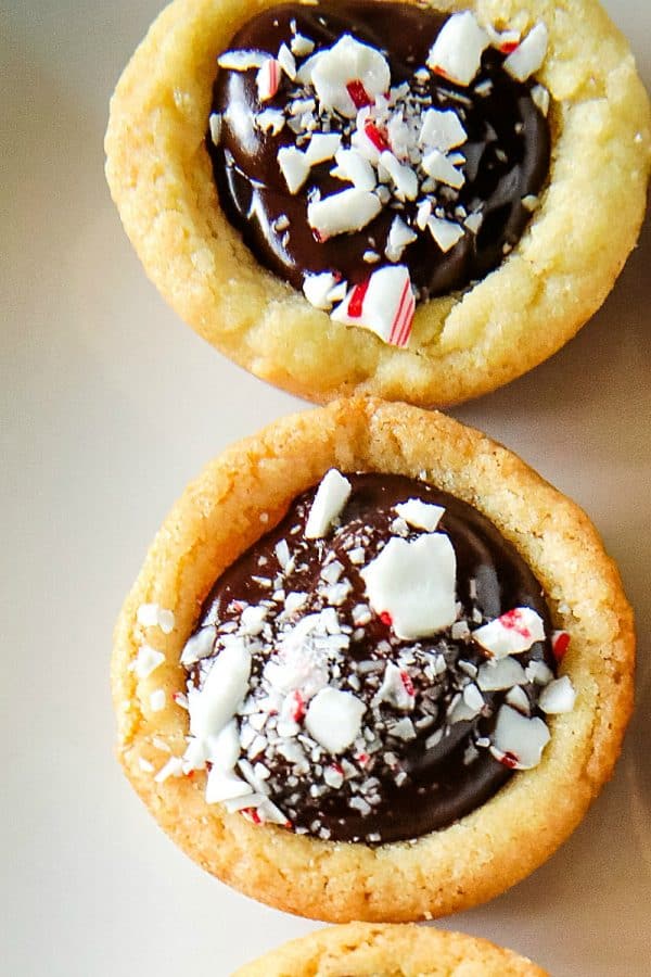 Chocolate Peppermint Sugar Cookie Cups - Tender sugar cookie cups brimming with chocolate ganache filling and crushed peppermint sprinkles! Three holiday favorites in one delicious treat!