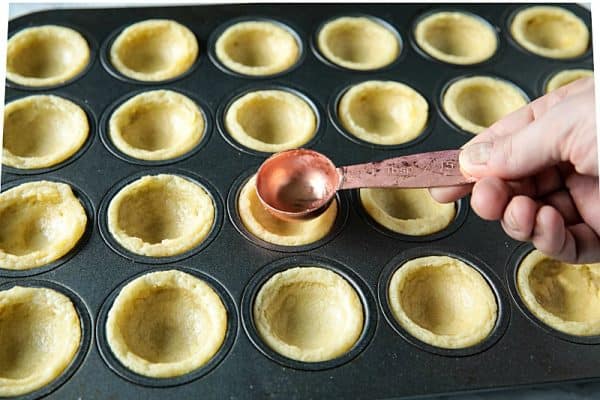 Pressing down sugar cookie cups to make well incenter