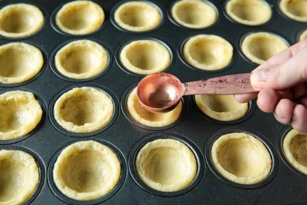 Pressing down bakied dough to make well with measuring spoon