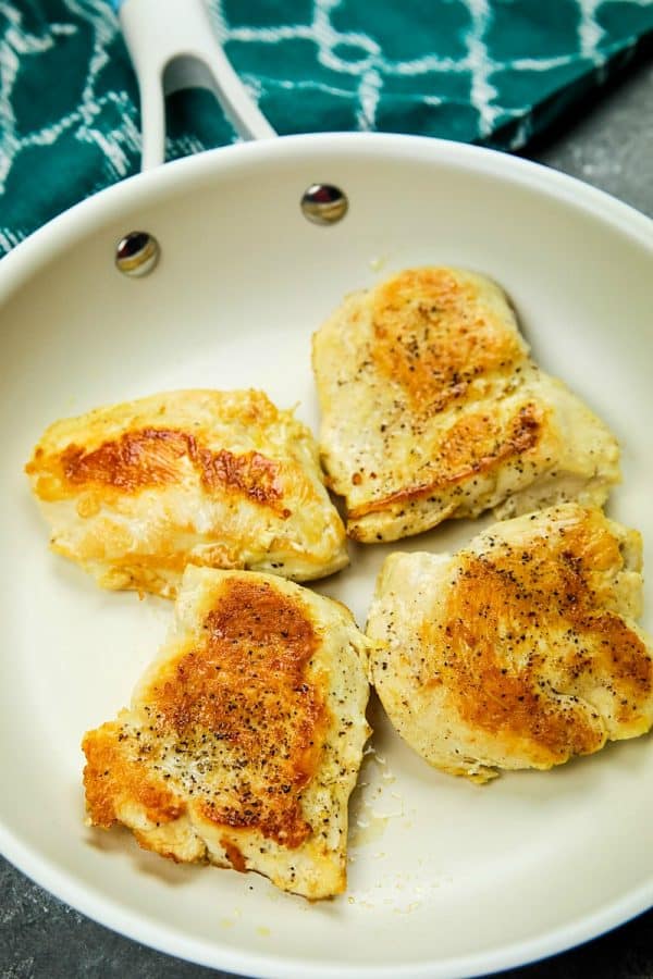 Chicken cutlets fried in white skillet