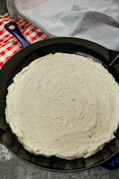 Cheese layer of pizza dip spread into cast iron skillet