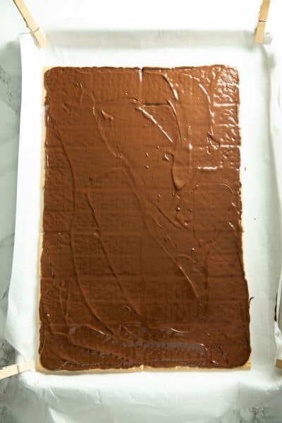 Melted chocolate layered over graham crackers on parchment