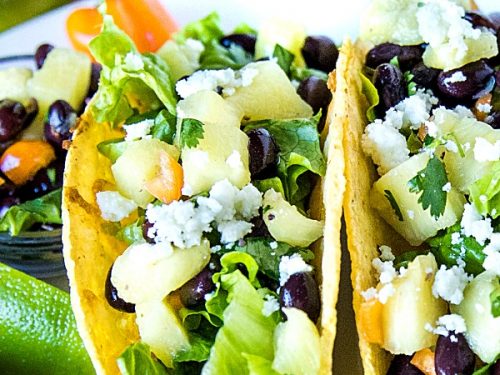 Easy Oven Chicken Tacos are seasoned shredded chicken stuffed into refried bean smeared crunchy shells and topped with cheese. Baked easy in the oven then loaded with spoonfuls of fresh pineapple salsa. #mustlovehomecooing #chickentacos #mexicanfood