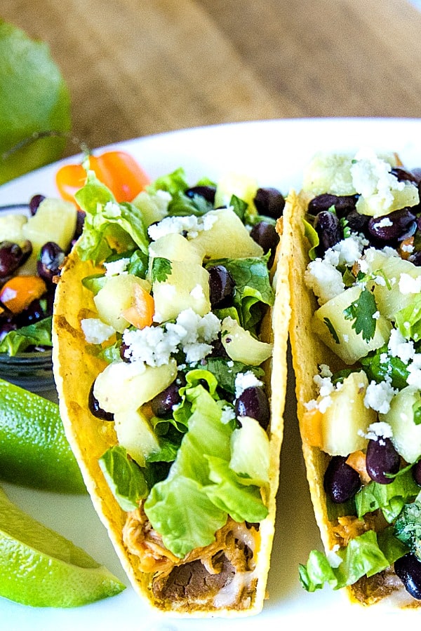 Easy Oven Chicken Tacos are seasoned shredded chicken stuffed into refried bean smeared crunchy shells and topped with cheese. Baked easy in the oven then loaded with spoonfuls of fresh pineapple salsa. #mustlovehomecooing #chickentacos #mexicanfood