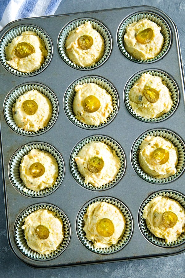 Jiffy cornbread muffins topped with jalapeno slices ready for the oven