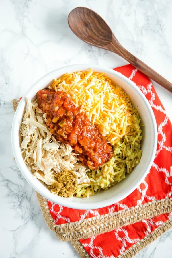 Chicken, rice salsa, cheese and cumin in white mixing bowl