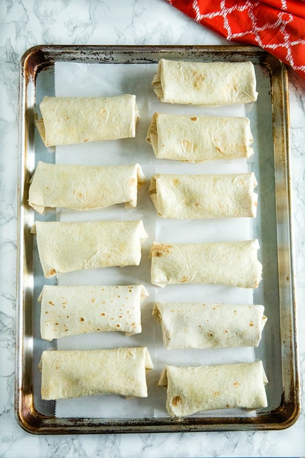 rolled chimichangas on sheet pan ready for baking