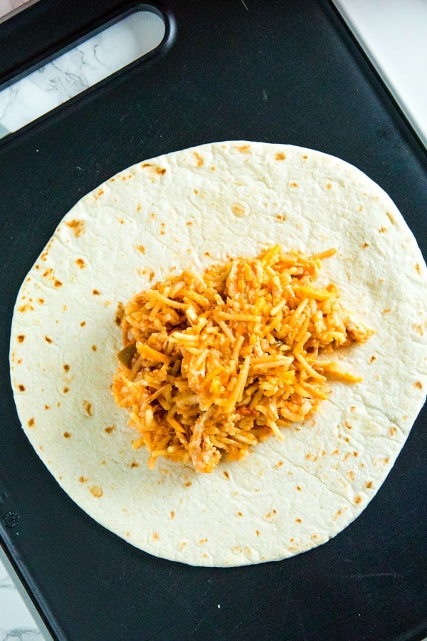 Tortilla with chimichanga filling on black cutting board