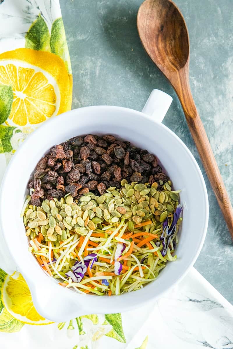 Easy Broccoli Slaw is a healthy, crunchy and sugar free blend of shredded broccoli, raisins and pepitas with an irresistible sweet and sour dressing. #mustlovehomecooking