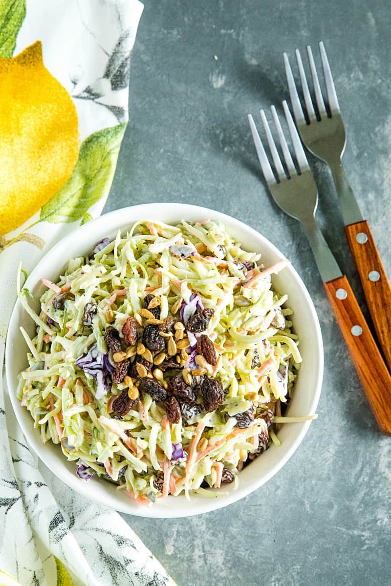 Easy Broccoli Slaw is a healthy, crunchy and sugar free blend of shredded broccoli, raisins and pepitas with an irresistible sweet and sour dressing. #mustlovehomecooking