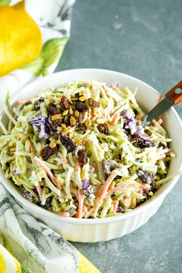 Easy Broccoli Slaw is a healthy, crunchy and sugar free blend of shredded broccoli, raisins and pepitas with an irresistible sweet and sour dressing. #mustlovehomecooking