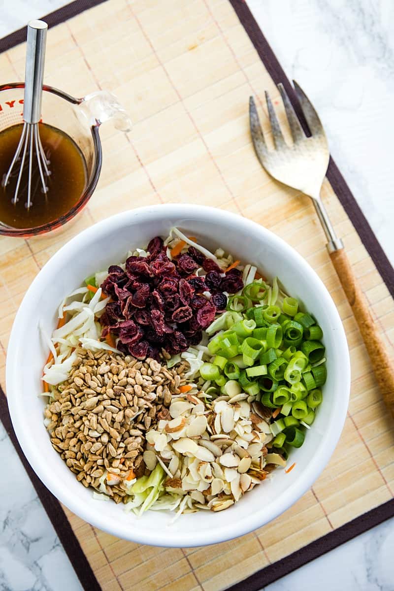 Midwest Cabbage Salad is a cold and crisp side dish made with shredded cabbage, green onions, dried cranberries, almonds. sunflower seeds and sweet dressing is fresh, healthy and stays crunchy in the refrigerator for several days! #mustlovehomecooking