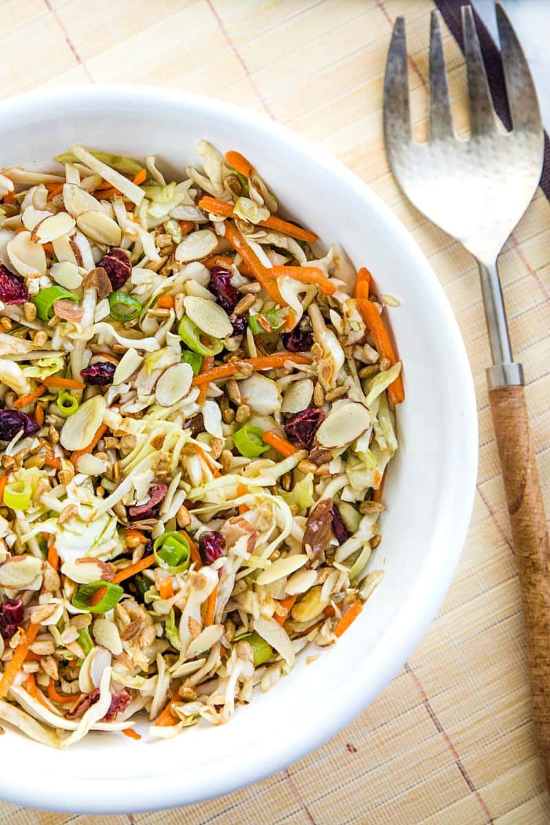 Midwest Cabbage Salad is a cold and crisp side dish made with shredded cabbage, green onions, dried cranberries, almonds. sunflower seeds and sweet dressing is fresh, healthy and stays crunchy in the refrigerator for several days! #mustlovehomecooking
