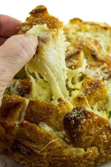 Pull apart three cheese garlic bread is a round sourdough loaf drizzled with garlic butter and stuffed with melting cheese. Crusty, and gooey hot bread made easy in under 30 minutes. #mustlovehomecooking